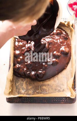 Woman pouring brownies cake aux framboises sur la plaque de cuisson de papier sulfurisé Banque D'Images