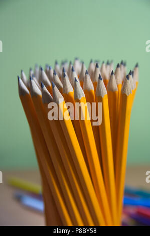 Close-up d'un groupe de crayons de couleur orange sur fond vert. Banque D'Images