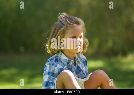 Mignon, jeune fille, assis et à côté, en vue, à l'extérieur en portrait. Communiqué de modèle # 114 Banque D'Images