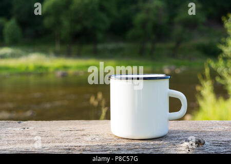 Camp blanc tasse à café émail immersive vue sur la rivière. Tasse vide pour la conception des maquettes de promotion. Banque D'Images