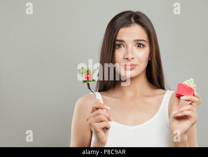 L'alimentation et l'excès de concept. Femme avec Cupcake et légumes sur fourche Banque D'Images