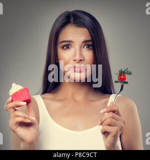 Femme malheureuse avec des aliments sains et malsains. Le surpoids, l'alimentation saine et l'alimentation Concept Banque D'Images