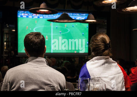 Photo d'un groupe de supporters français dans un restaurant à regarder sur un écran géant de la demi-finale match France Belgique, au cours de la Coupe du Monde FIFA 2018, qui a vu la victoire de l'équipe française. La Coupe du Monde de Football 2018 est la 21e Coupe du Monde de la FIFA, un tournoi international de football contesté par le l'équipe nationale des associations membres de la FIFA une fois tous les quatre ans. Il est actuellement en cours en Russie à partir du 14 juin et se terminera avec la finale le 15 juillet 2018 Banque D'Images