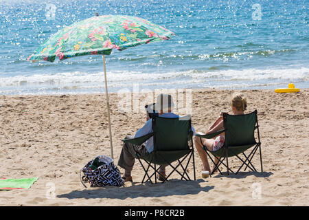 Bournemouth, Dorset, UK. 11 juillet 2018. Météo France : un autre jour ensoleillé chaud de Bournemouth avec aucun signe de la canicule se terminant pourtant, comme chef de la mer sunseekers à plages de Bournemouth. Couple de chaises sous un parasol coloré le soleil brille. Credit : Carolyn Jenkins/Alamy Live News Banque D'Images