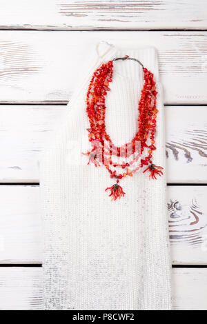 Collier en pierre rouge sur pull en laine blanche. Banque D'Images