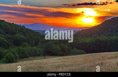 L'incroyable beauté du coucher de soleil avec une lumière rouge jaune sur les sommets des montagnes et de beaux espaces verts de la couleur de la nature. . Pour votre des Banque D'Images