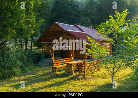 Sauna dans une maison de bois de sciage et de bancs avec une table pour reste debout sous un baldaquin. Tout est situé au milieu de la belle nature d'une Banque D'Images