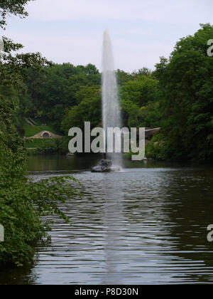 Une énorme fontaine au milieu du lac sur fond de belles pelouses et arbres verts . Pour votre conception Banque D'Images