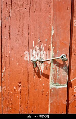 Close up d'un ancien loquet de l'œil sur l'extérieur d'un hangar grange rouge pour le garder fermé et verrouillé/sécurisé sur une vieille ferme dans le Wisconsin, USA. Banque D'Images