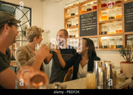 Smiling friends cheering avec boissons dans un bar branché Banque D'Images