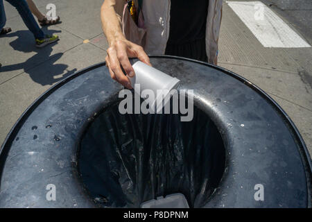 Un passant dispose de son gobelet de styromousse dans une corbeille à New York, le samedi 30 juin, 2018. Après des années de disputes New York City's interdiction de polystyrène, qui est utilisé dans les conteneurs, et difficile à recycler, il prend effet le 1er janvier 2019. D'autres villes ont déjà interdit le polystyrène qui n'est pas biodégradable. (Â© Richard B. Levine) Banque D'Images