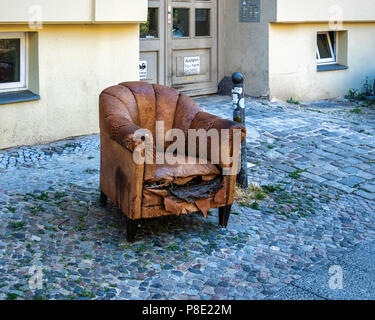 Vieille chaise en cuir jetés sur les trottoirs de la ville. Meubles abandonnés sur la chaussée urbaine Banque D'Images