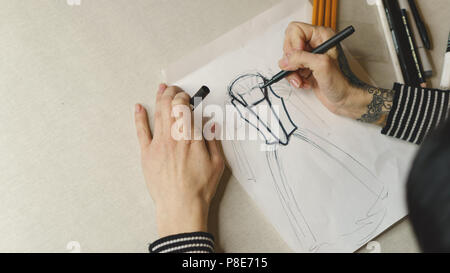 Mode Fille attire l'esquisse d'une robe de soirée. Le tournage de près. Elle peint avec des marqueurs. Banque D'Images