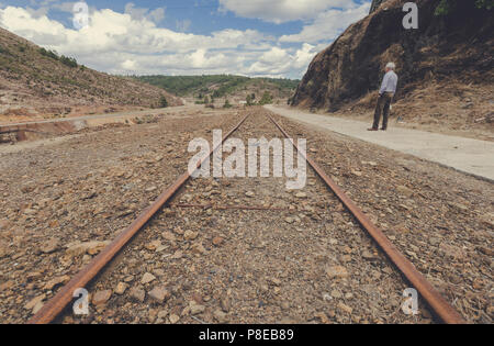 Personnes âgées homme debout et à l'opposé de la voie ferrée du train se perdre sur l'horizon dans la Zaranda mines entre les villes de Nerva et Riot Banque D'Images