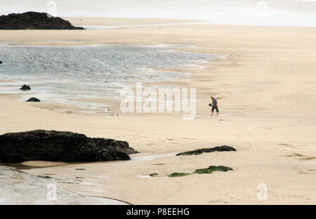 Silhouette d'un homme marchant dans l'immense plage de Newquay, une destination populaire pour les surfeurs. Newquay, Cornwall, UK Banque D'Images