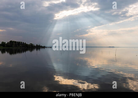 Parfaitement symétrique et vue spectaculaire d'un lac, avec des nuages, le ciel et les rayons du soleil reflétant sur l'eau Banque D'Images