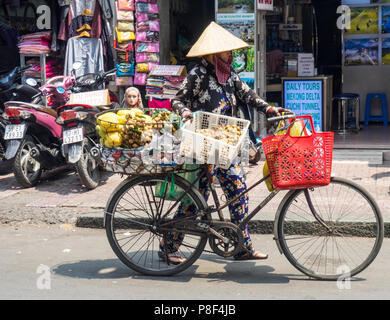 La vie de tous les jours, un vendeur de rue femme vendant des fruits de son vélo dans la rue à Ho Chi Minh City, Vietnam. Banque D'Images