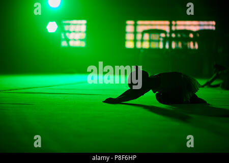 Jeune fille gymnaste exécute l'athlète éléments acrobatiques dans un pittoresque vert lumière. Banque D'Images