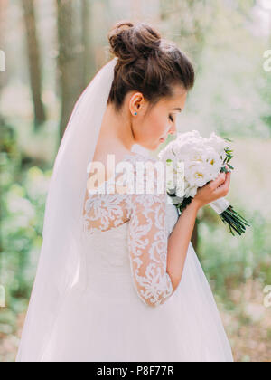 La charmante épouse, c'est sentir le mariage bouquet de pivoines blanches. La vue arrière. Banque D'Images