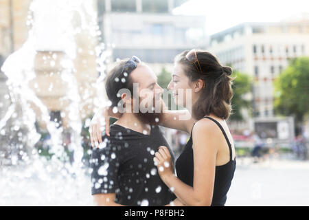 Couple standing par une fontaine d'eau hugging Banque D'Images