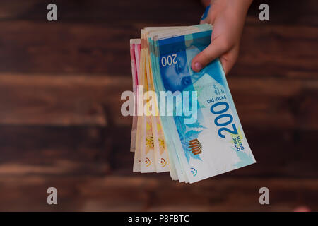 Femme tenant un tas de billets Nouveau shekel israélien dans ses mains Banque D'Images