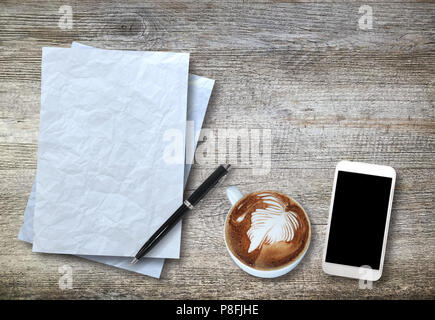Vue de dessus de papier blanc, smartphone, stylo et tasse de café sur fond de bois. Banque D'Images