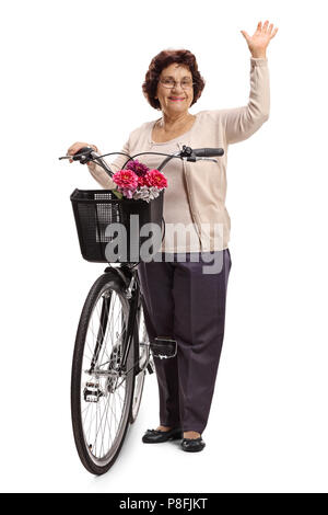 Portrait d'une femme âgée avec un vélo en agitant à l'appareil isolé sur fond blanc Banque D'Images