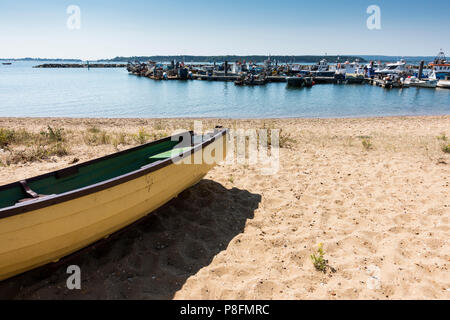 Une noyade vide bateau sur le sable à côté de port de Poole avec bateaux de pêche amarrés dans l'arrière-plan, Poole, Dorset, Royaume-Uni Banque D'Images