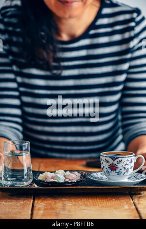 Une femme de café turc dans une tasse de café turc traditionnel sur un plateau de cuivre traditionnel un verre d'eau avec un pétale de rose à l'intérieur et en turc Banque D'Images