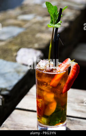 Un Pimm's dans un verre sur une table en bois - un brin de menthe comme un arbre Banque D'Images