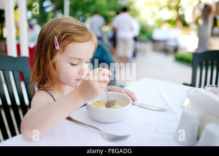 Cute little girl eating cereal outdoors Banque D'Images