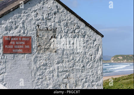 Un signe sur le mur blanchi à la chaux de l'ancien parc blanc Bay Youth Hostel avertissement que la plage n'est pas sécuritaire de le bain. Bushmills, County Antrim, Northern Banque D'Images