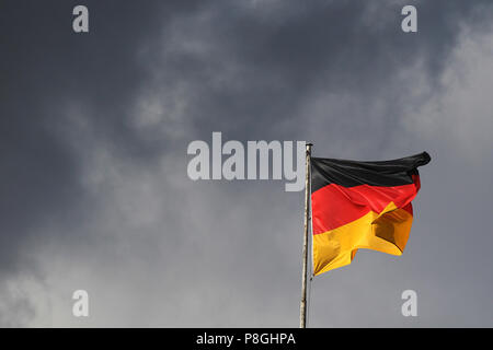 Berlin, Allemagne, drapeau allemand soufflant en face de ciel noir Banque D'Images