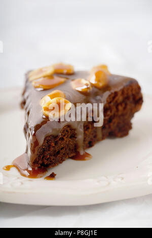 Close up d'un morceau de brownie gâteau au caramel au beurre salé et des cacahuètes grillées Banque D'Images