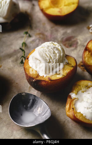 La fonte de la glace à la vanille servi dans un bain de moitié de pêches et de nectarines grillées Banque D'Images