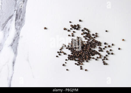 Heap de poivre noir concassé sur du marbre blanc texture background. Vue de dessus, de l'espace. Banque D'Images
