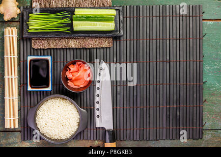 Ingrédients sushis traditionnel : riz, filet de saumon, gingembre, concombre, ciboulette, sauce soja et bambou foncé sur fond rustique. Arrière-plan de l'alimentation asiatique Banque D'Images