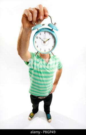 Man holding up une horloge en face de son visage montrant l'heure. Banque D'Images