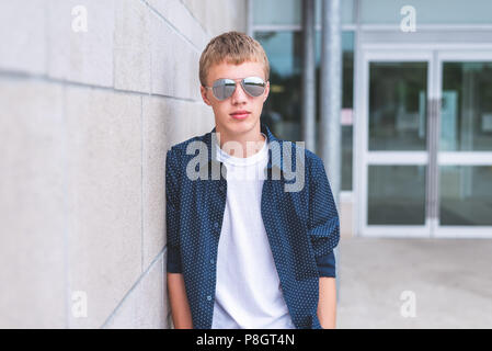 Adolescents graves portant des lunettes de soleil et appuyé contre un mur de briques. Banque D'Images