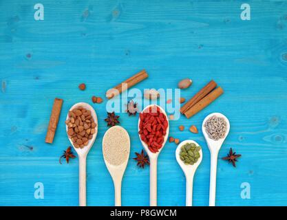 Concept de tableau avec des graines et fruits aromatiques dans des cuillères en bois, sur fond bleu, télévision, table top, copy space Banque D'Images