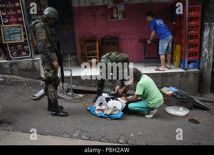 Rio de Janeiro, Brésil. 11 juillet, 2018. Recherche d'une valise de soldats un piéton lors d'une intervention à la Favela Pavao Pavaozinho. Face à la vague de criminalité, le gouvernement de Temer a créé un nouveau ministère de la sécurité publique en février 2018. De plus, une invention militaire a été commandé à Rio de Janeiro. Crédit : Fabio Teixeira/dpa/Alamy Live News Banque D'Images