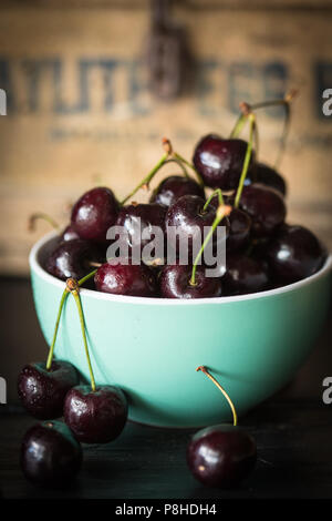 Petit bol vert rempli de cerises mûres fraîchement cueillies Banque D'Images