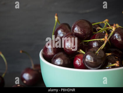 Petit bol vert rempli de cerises mûres fraîchement cueillies Banque D'Images