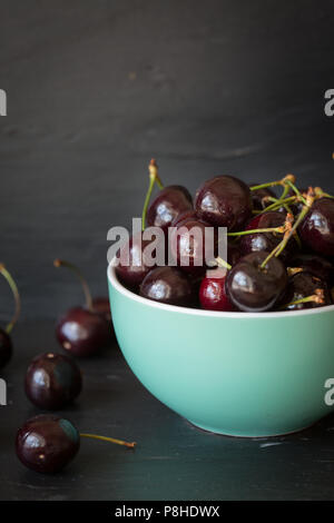 Petit bol vert rempli de cerises mûres fraîchement cueillies Banque D'Images