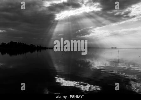 Parfaitement symétrique et vue spectaculaire d'un lac, avec des nuages, le ciel et les rayons du soleil reflétant sur l'eau Banque D'Images