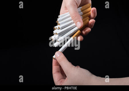 La main est de donner des paquet de cigarettes sur fond noir Banque D'Images