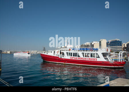 Un bateau d'excursion attend pour lancer sa prochaine croisière alors que le ferry pour La Valette Sliema cours des voiles Banque D'Images