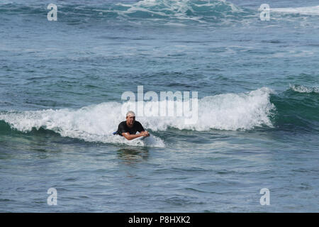 Les surfeurs d'essayer leur sport sur les vagues de l'océan au large de la plage de sable à Halona Cove. Plage de sable fin, Halona Cove, l'île d'Oahu, Hawaii, USA. Banque D'Images