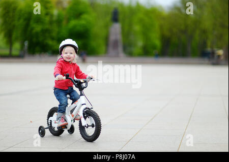 Adorable bébé fille équitation son premier vélo Banque D'Images