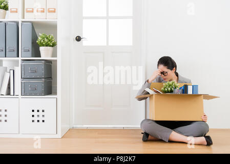 Femme Asiatique assis sur le plancher en bois et ne sait pas quoi faire pour faire face à la tâche complexe. Banque D'Images